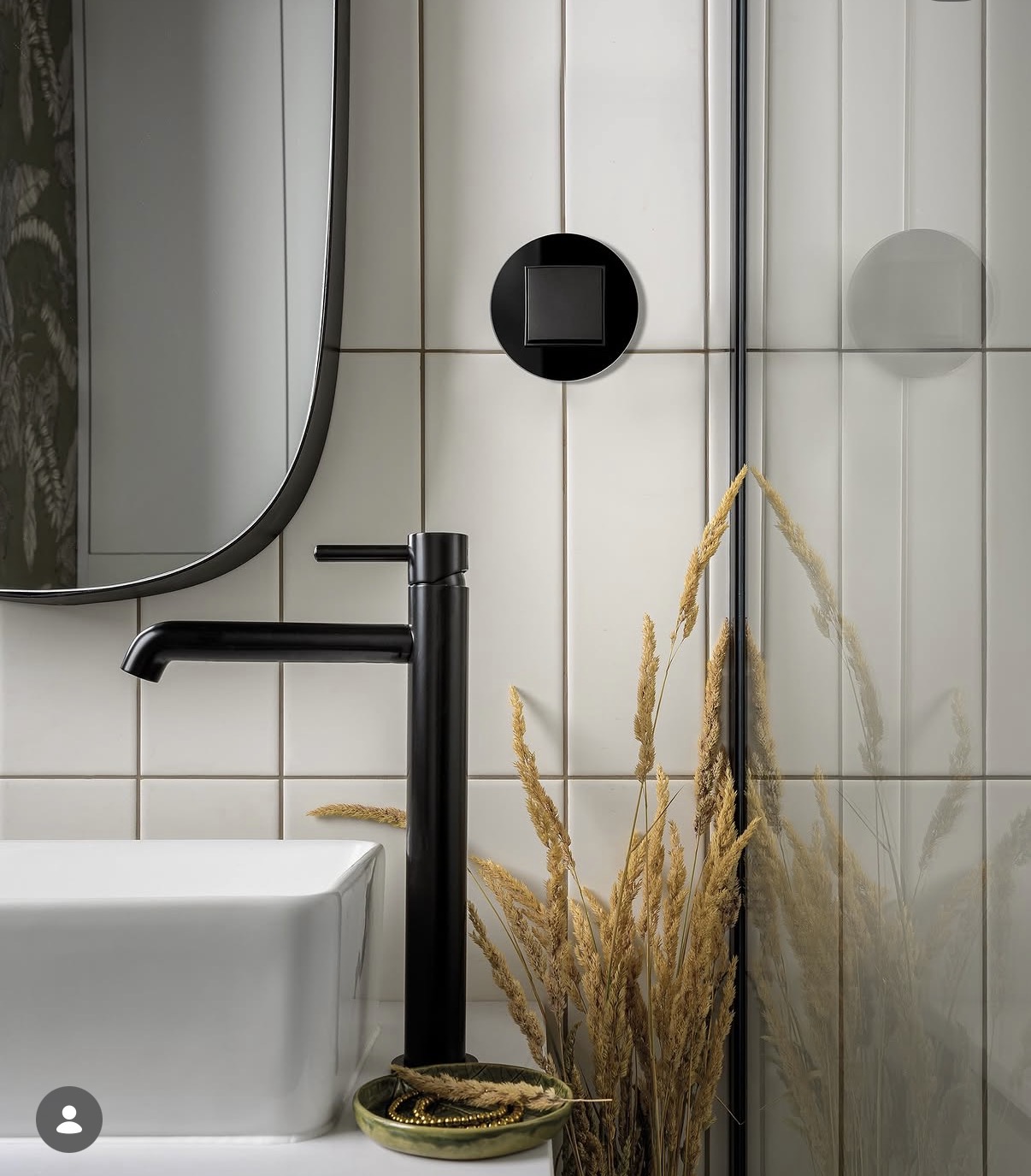 Round black single switch on vertical white bathroom tile