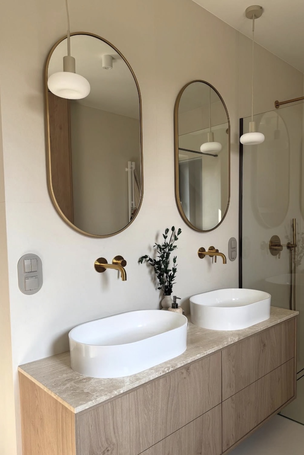 Taupe oval switch and socket plate above a double bathroom vanity